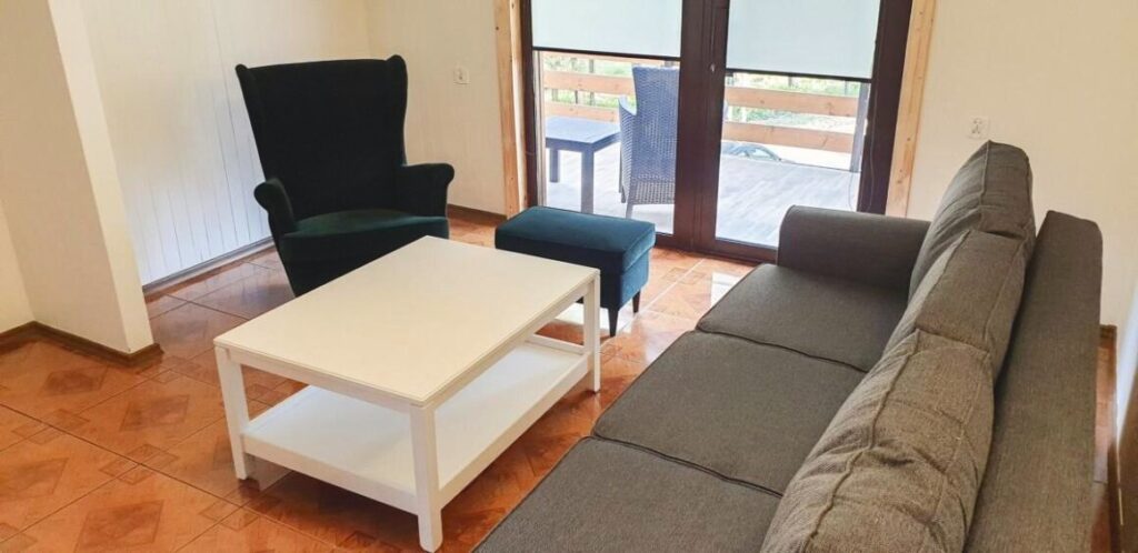 Salon w domku Tarnawka z kanapą, fotelem i wyjściem na balkon
